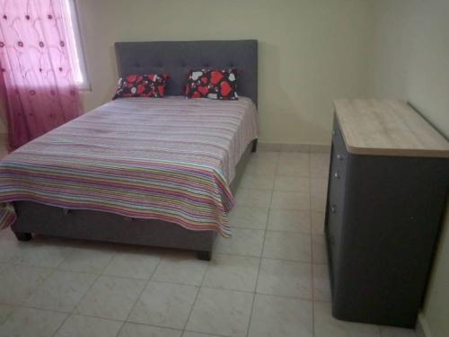 Ghana Town的住宿－Costal Road hideout!，一间卧室配有一张大床和一张木桌