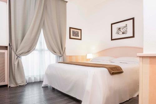 a bedroom with a white bed and a window at Hotel Poli in Castelnovo di Sotto