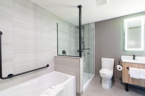 a bathroom with a tub and a toilet and a sink at Sandman Signature Dartmouth Hotel & Suites in Halifax