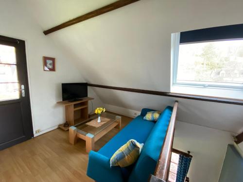 un salon avec un canapé bleu et une fenêtre dans l'établissement la cascatelle, à Ganzeville