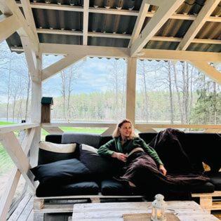 a woman sitting on a couch in a living room at Miškas Arjola in Kaltanėnai