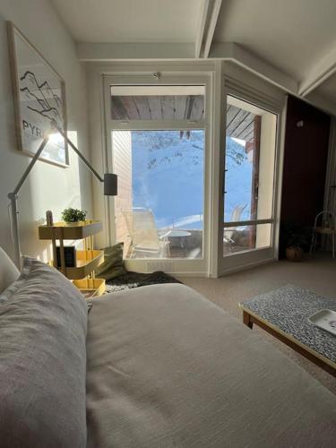 une chambre avec un lit et une grande fenêtre dans l'établissement La Mongie - Studio rénové avec terrasse plein sud, à Bagnères-de-Bigorre