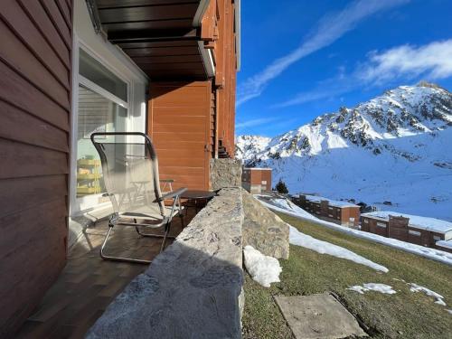 a chair sitting on a porch with a snowy mountain at La Mongie - Studio rénové avec terrasse plein sud in Bagnères-de-Bigorre