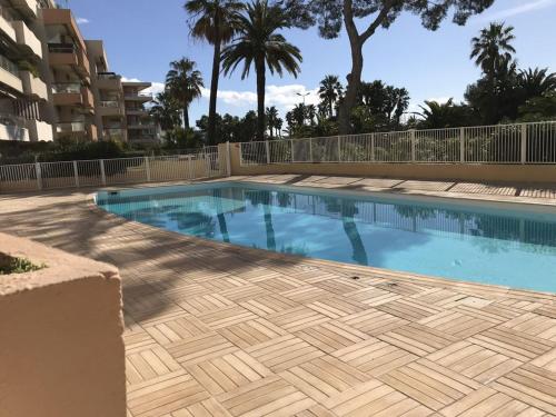 - une piscine dans un complexe avec des palmiers dans l'établissement BEAU RIVAGE SAINT RAPHAEL 83700 FRANCE, à Saint-Raphaël