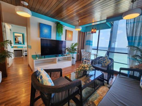uma sala de estar com televisão e uma sala de estar com sofá em The Hive Beach em Malé