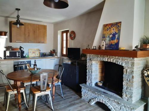Il comprend un salon avec une cheminée, une table et une cuisine. dans l'établissement Maison de charme Orezza Haute-Corse Castagniccia, à Carpineto