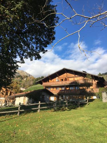 un gran edificio de madera con una valla en un campo en Wonderful apartment overlooking the Swiss alps, en Château-d'Oex