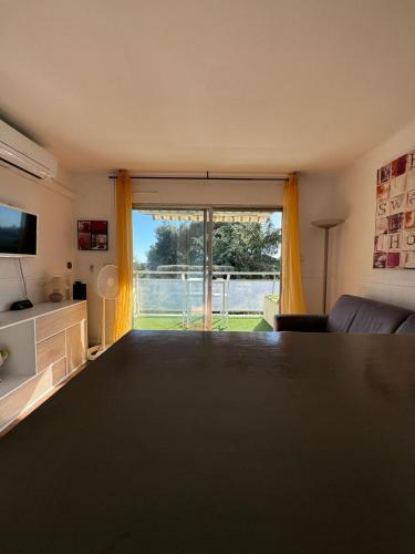 un salon avec une table et une grande fenêtre dans l'établissement Beau studio climatisé face à la mer, à La Ciotat