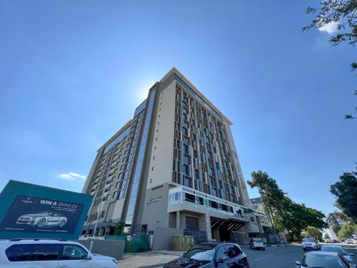 un edificio alto con coches estacionados en un estacionamiento en CGRSA Apartments Sandton, en Johannesburgo