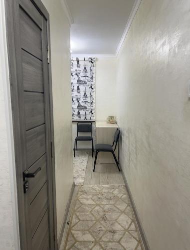 a hallway with a door and a chair in a room at Апартамент 1 комнатный in Taraz