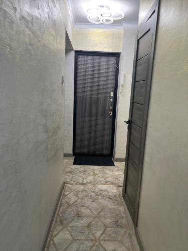 a hallway with a black door and a tile floor at Апартамент 1 комнатный in Taraz