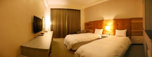 a hotel room with two beds and a television at Jade Garden Hote in Gukeng