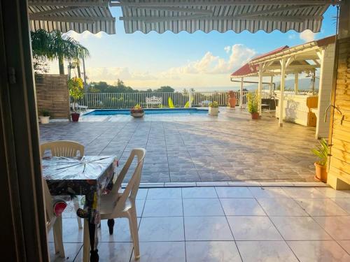 a patio with a table and chairs and a pool at Appartement charmant à Rivière-Pilote avec piscine privée in Rivière-Pilote