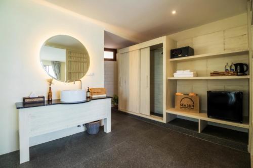 een badkamer met een wastafel met een spiegel en een tv bij Sea Sun Bed & Beyond in Koh Samui 