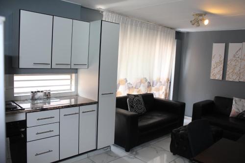 a kitchen with white cabinets and a black chair at Beyond Comfort Apartment in Pretoria