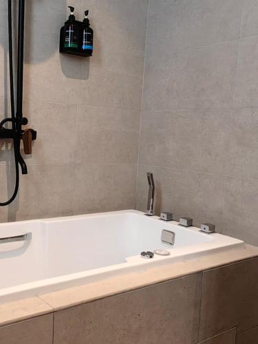 a bathroom with a bath tub with two bottles on the wall at The Palm Suite@Chusan in George Town