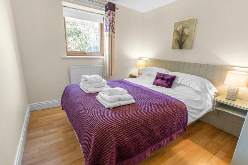 a bedroom with a bed with towels on a purple blanket at Harvest Cottage and Holly Barn in Yarm