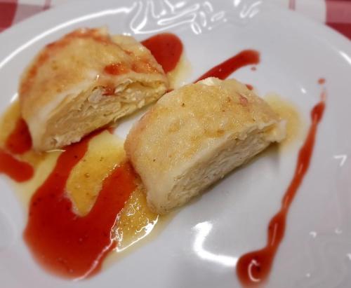 two pieces of food on a white plate with sauce at PLANINSKA KOČA NA GOZDU in Kranjska Gora
