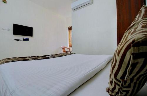 1 dormitorio con 1 cama blanca y TV en la pared en Grand Stay, en Chennai