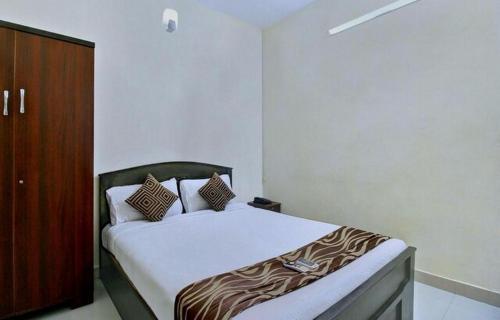 1 dormitorio con 1 cama y armario de madera en Grand Stay, en Chennai