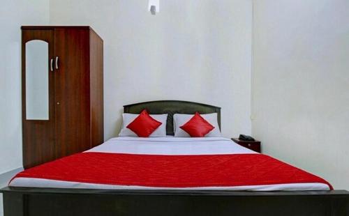 1 cama con almohadas rojas en una habitación en Grand Stay, en Chennai