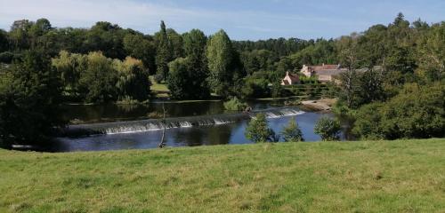 a river with a waterfall in the middle of a field at La Vieille Ferme in Donnay