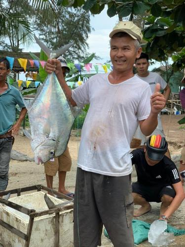 a man is holding a fish in a bag at Santa Sea Villa in Hoi An