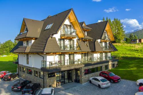 a large house with cars parked in a parking lot at Aparthotel Zakopane in Zakopane