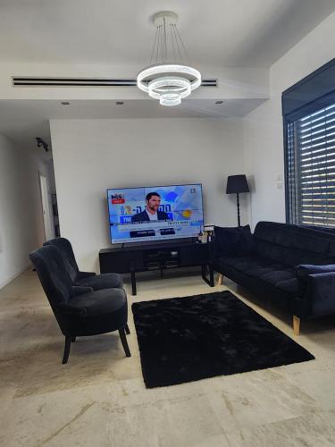 a living room with a couch and a flat screen tv at penthouse in Herzliya