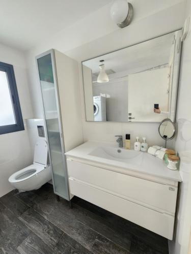 bagno bianco con servizi igienici e lavandino di penthouse a Herzelia
