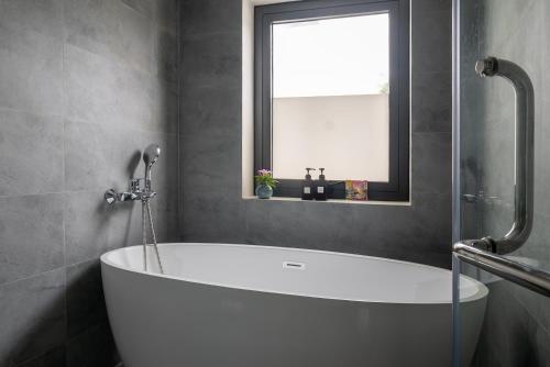 a white bath tub in a bathroom with a window at Hajime Homestay Hue in Hue
