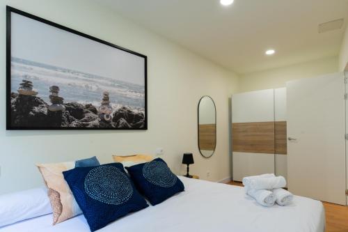 a bedroom with a white bed with blue pillows at BILBAO NORTH SHORE APARTMENTS in Bilbao