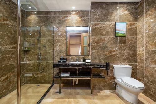 La salle de bains est pourvue de toilettes, d'un lavabo et d'une douche. dans l'établissement Phoenix Hill Hotel Dongguan - Golf Course Shop, à Dongguan