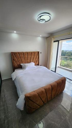 un grande letto in una camera da letto con una grande finestra di Gatundu Heights a Nairobi