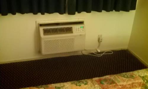 a room with a bedroom with a air conditioner on the wall at National 9 Inn in Tonopah