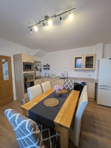 una cucina con tavolo in legno e sedie bianche intorno di New Fully equipped 2 bedroom house. Sleeps 6 a Brockhurst