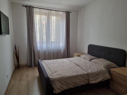 a bedroom with a bed and a large window at Joy Apartman in Sovata