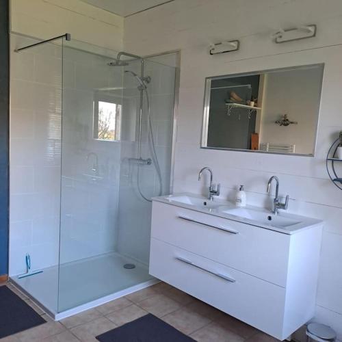 une salle de bain blanche avec une douche et un lavabo dans l'établissement Gîte Le Pavillon dans le parc du Château Lescaut, à Montignac-de-Lauzun