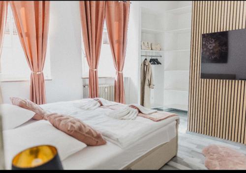 a bedroom with a white bed with orange curtains at Ferienwohnung Zentrum Erding in Erding