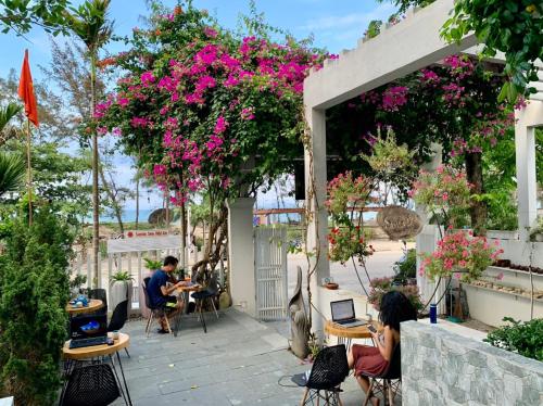 a group of people sitting at tables on a patio with flowers at Santa Sea Villa in Hoi An