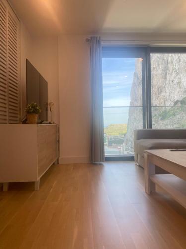 Habitación con ventana grande, cama y TV. en CP Top floor luxury studio with spa and pool, en Gibraltar