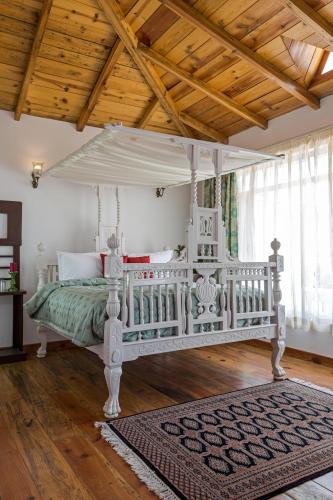 a bedroom with a white canopy bed with a rug at Te Aroha By Shervani in Mukteswar