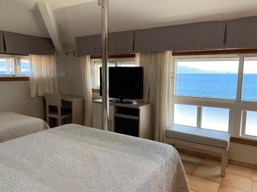 una camera da letto con un letto e una TV a schermo piatto di Hotel Playa a Cangas de Morrazo