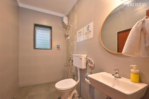 a bathroom with a sink and a toilet and a mirror at EKOSTAY - Omega Villa in Igatpuri