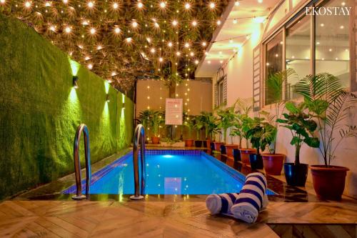 a swimming pool in a building with lights and plants at EKOSTAY - Omega Villa in Igatpuri