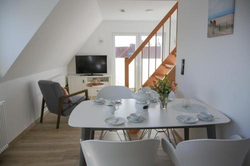 a white dining room with a table and chairs at Haus Sandkorn in Baltrum