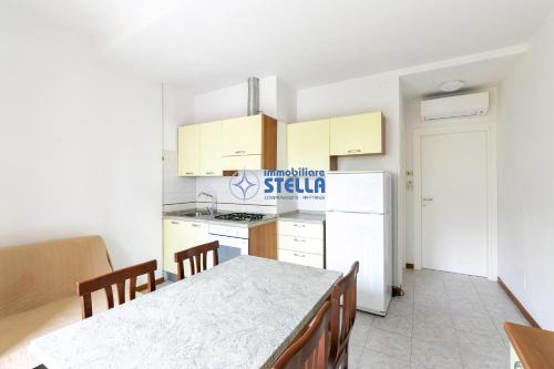 a kitchen with a table and a white refrigerator at Residence Adriatica in Lido di Jesolo