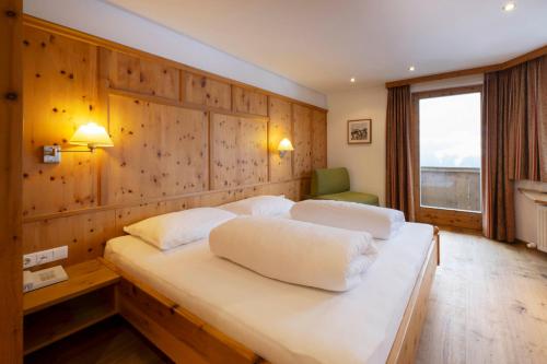 a bedroom with two beds with a wooden wall at Hotel Bergkranz in Mieders