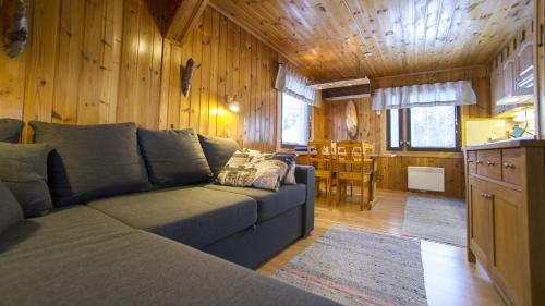 a living room with a blue couch and a kitchen at Ylläksen Yöpuu in Äkäslompolo