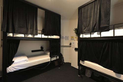 シドニーにあるVENUS Potts Point - FEMALE ONLY HOSTEL - Long stay negotiableの二段ベッド2組(黒いカーテン付)が備わる客室です。